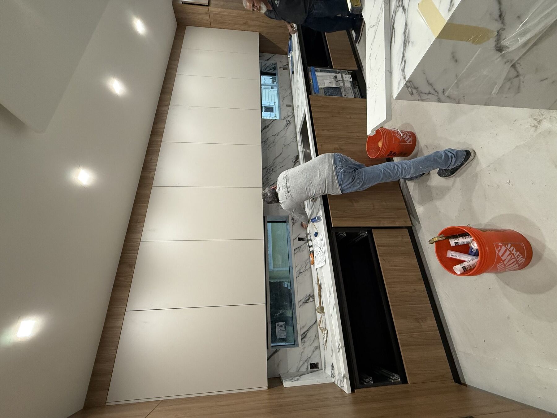 Installer fitting cabinetry and marble backsplash on site